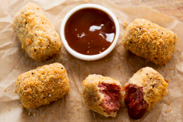 Crispy fried snack pieces with a dipping sauce on parchment paper