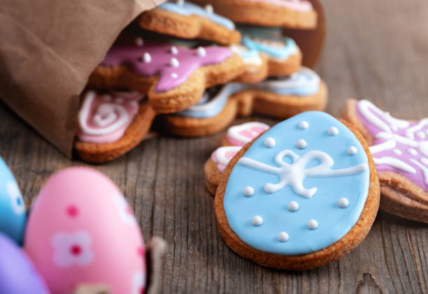 Colorful decorated cookies and Easter eggs on a wooden surface.