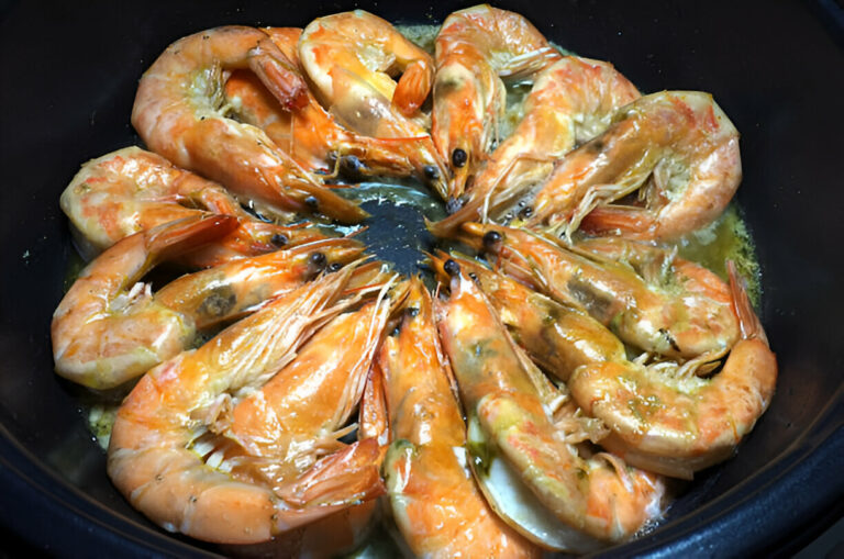 A circular arrangement of cooked shrimp in a black dish