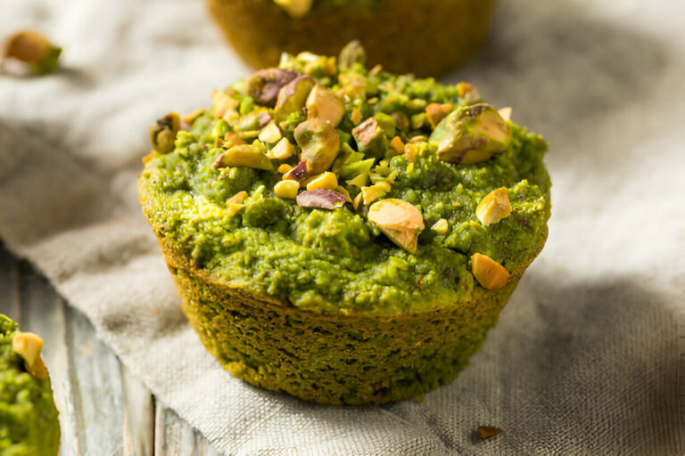 Green muffin topped with chopped nuts on a textured cloth